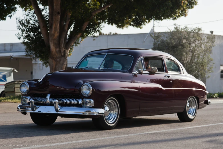 an old vintage maroon car in the street