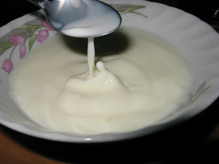 a spoon drizzling soing in a white bowl