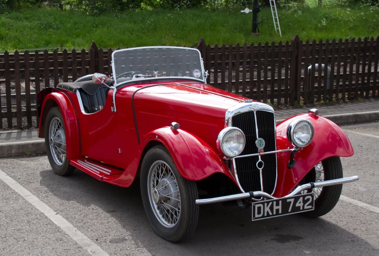 an old style red car sitting in a parking lot