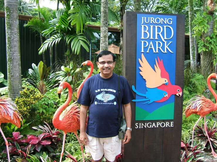 a man stands next to a sign for a bird park