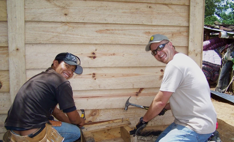 two men are smiling for the camera while working on a building