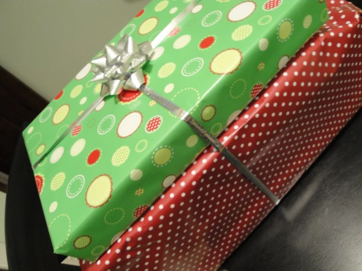 a green gift box with red polka dot design on it