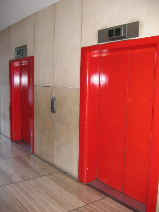 a red metal elevator beside a white wall