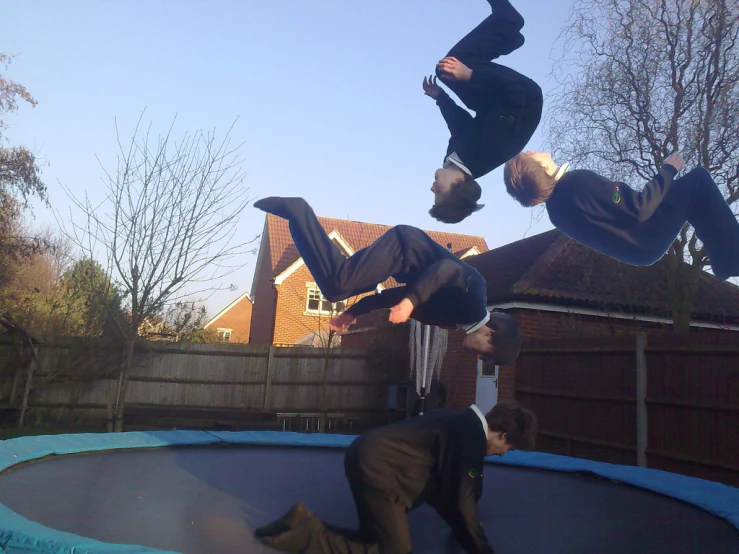 three men are doing tricks on a trampoline