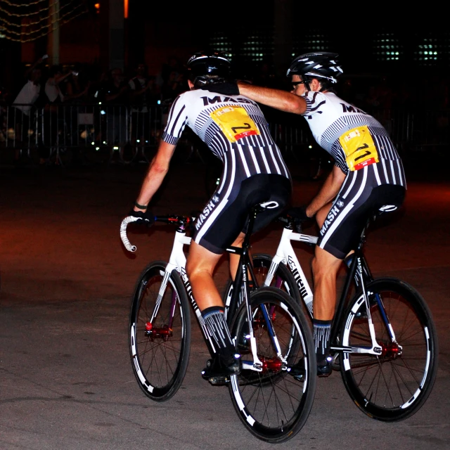 two men wearing bikes on a road during night