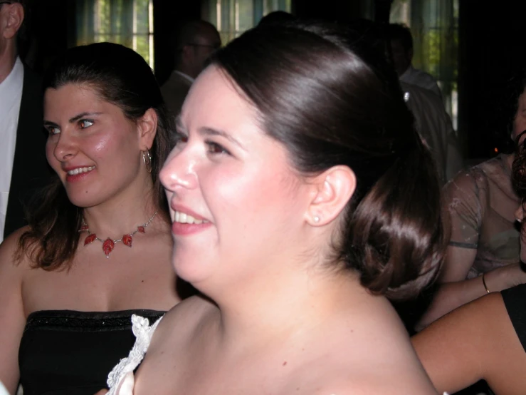 two women wearing dresses are talking together at a party