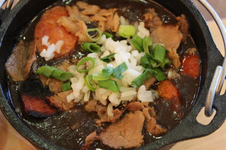 a bowl of rice, meat and vegetables sitting on a table