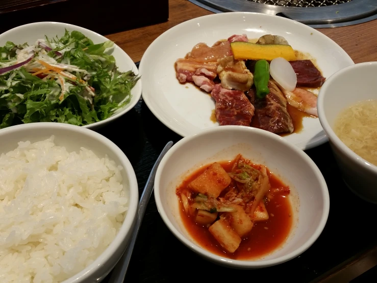 some bowls are sitting on a table filled with rice and meats