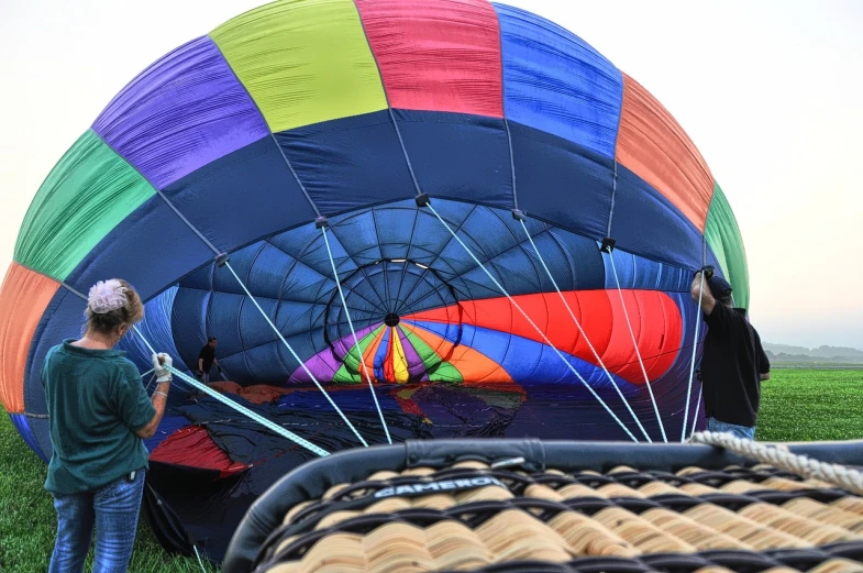 a person standing in a field next to a large  air balloon