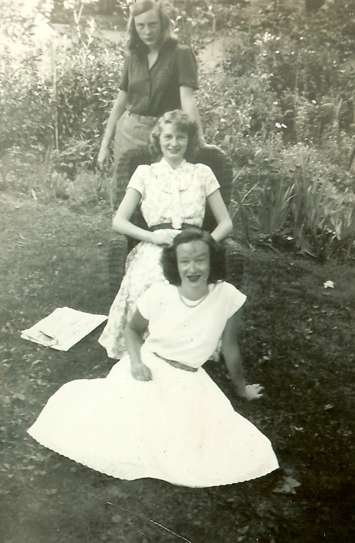 three women and two girls are seated in an open field