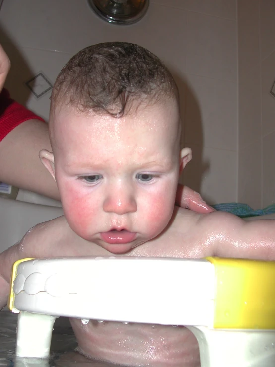 a little boy standing in a bath tub and being bathed