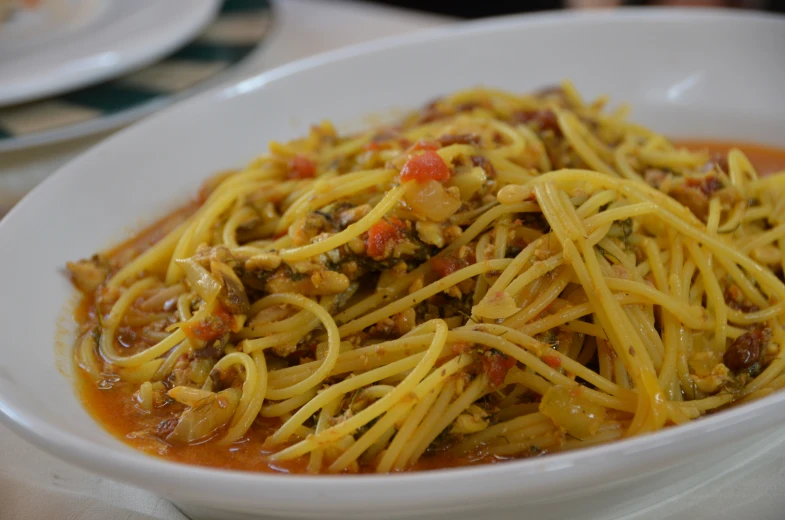 a bowl of spaghetti with meat, sauce and vegetables