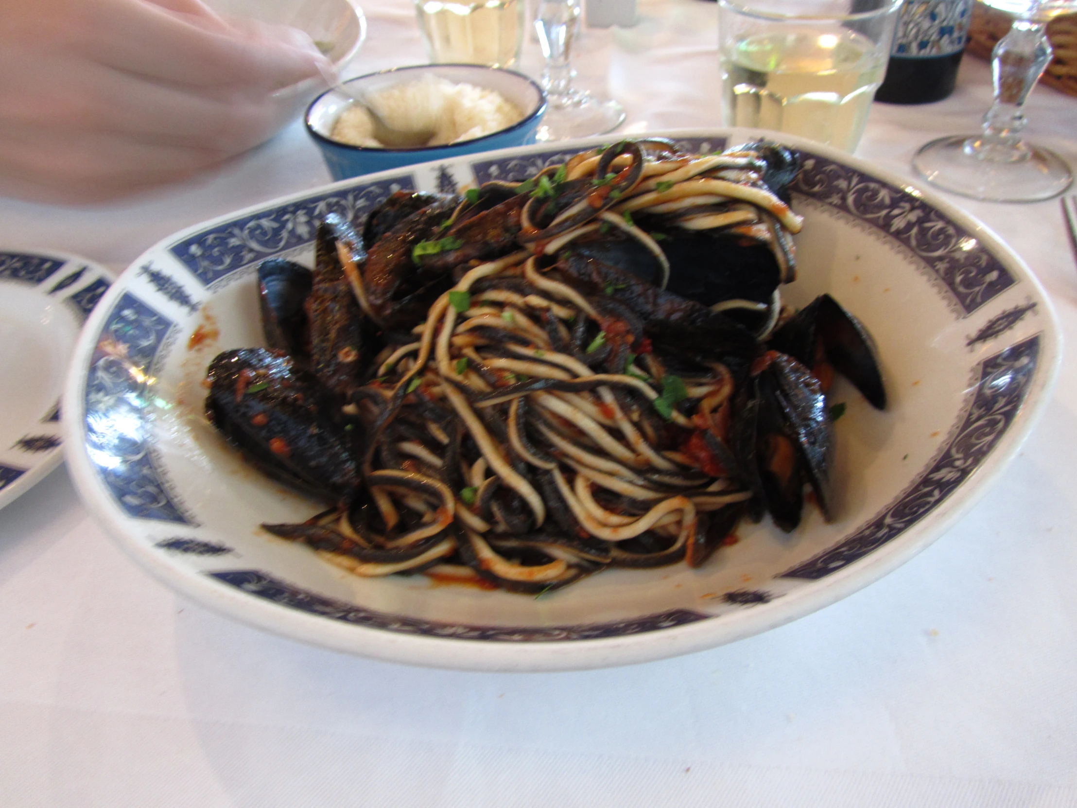 a bowl full of spaghetti and clams on a white table