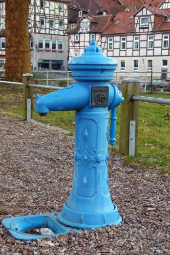 a blue fire hydrant is in the foreground with a building in the background