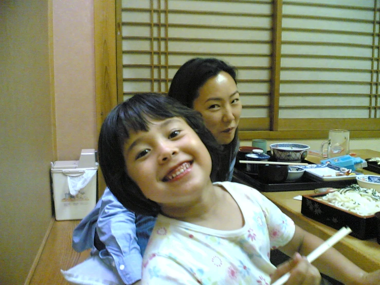 two girls sitting at a table in front of a window