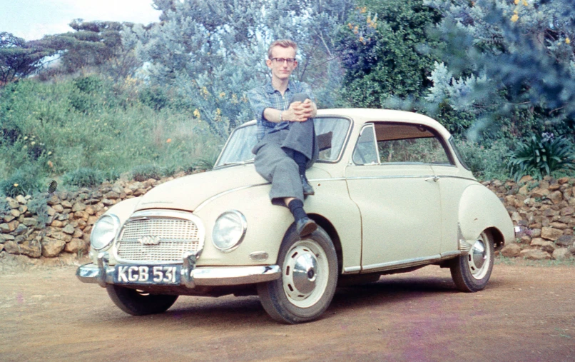 a man sitting on top of an old white car