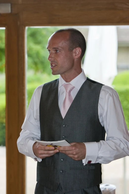 a well dressed man reads a piece of paper