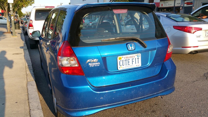 the back end of a blue compact car parked on a street