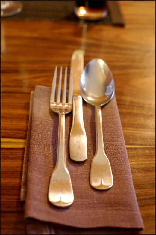 three silver utensils are sitting on the folded napkin