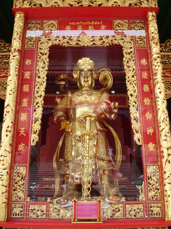 gold statue of sitting on red floor with decorative wall