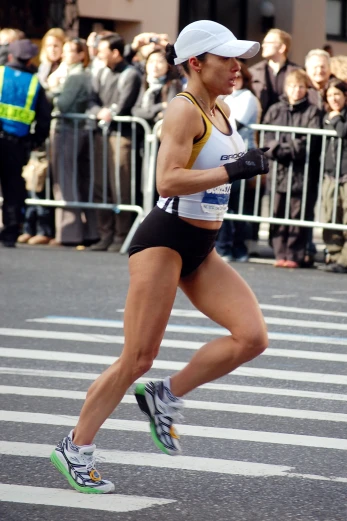 woman running in marathon wearing black shorts and cap