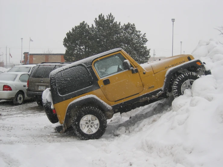 a yellow jeep is covered in snow outside