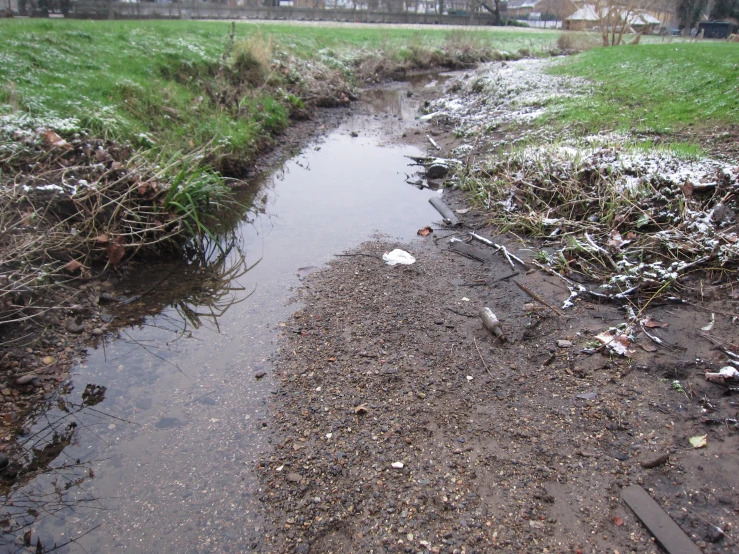 a small river in a field with snow on the ground