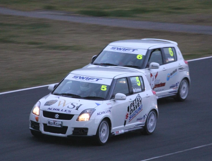 two cars racing on a race track during the day