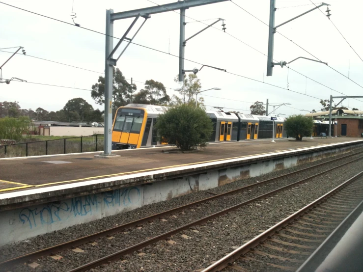 two electric trains stopped in front of a platform at an industrial station