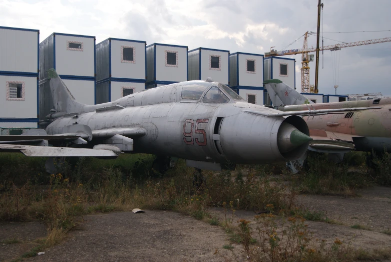 a fighter jet sits next to several storage containers