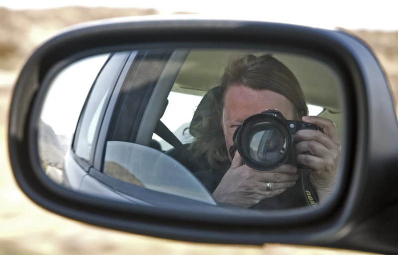 a woman takes a po in the rear view mirror of a car