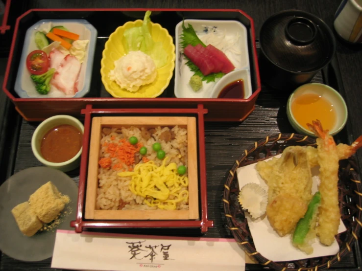 plates and trays of food with rice and dipping sauce