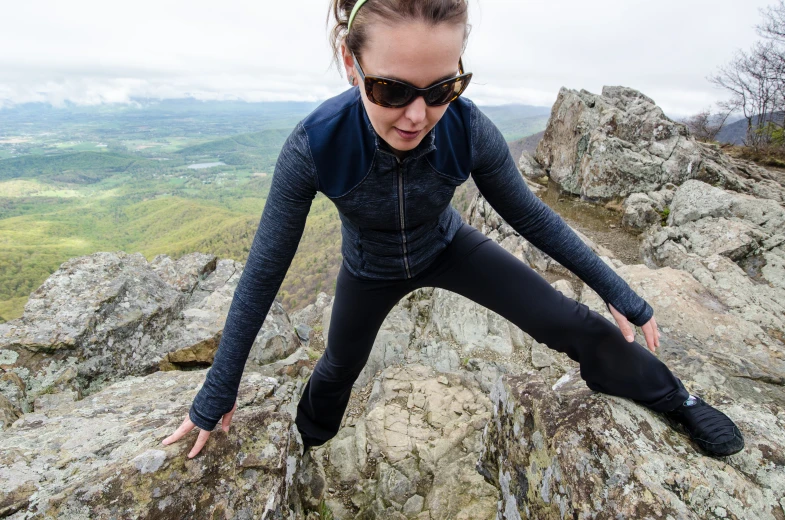 a woman sitting on top of a rocky cliff