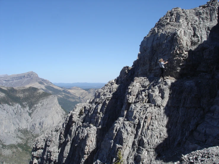 a man standing on top of a cliff next to a mountain