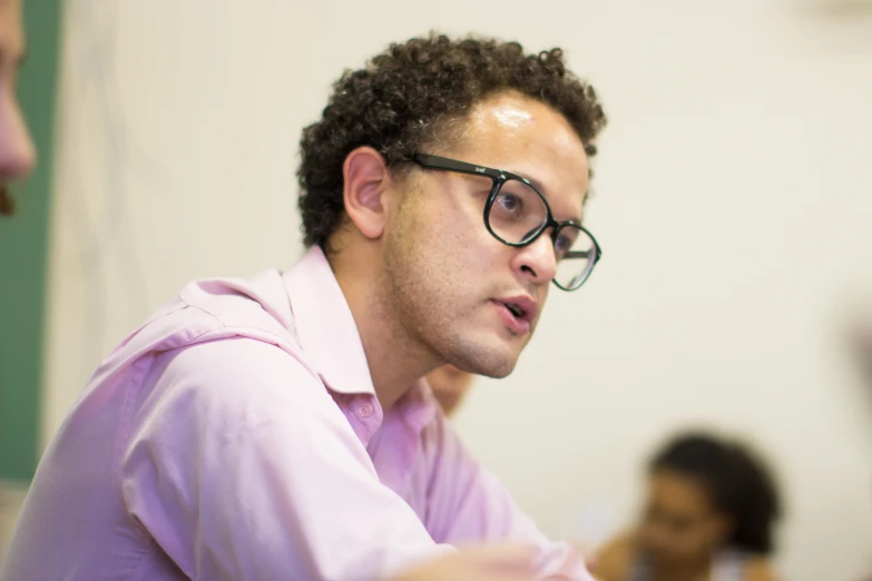 a man with glasses wearing a pink shirt