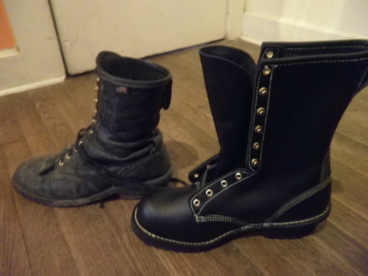 pair of black leather boots sitting on hard wood floor