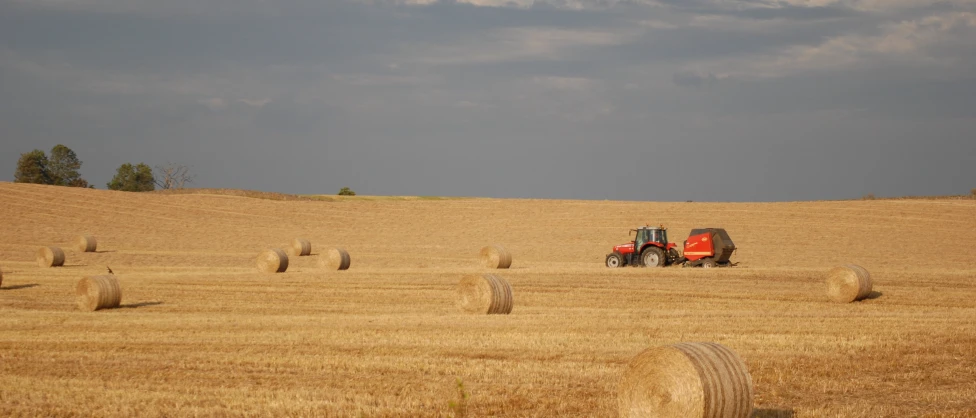 a farmer drives his red tractor across a farm field