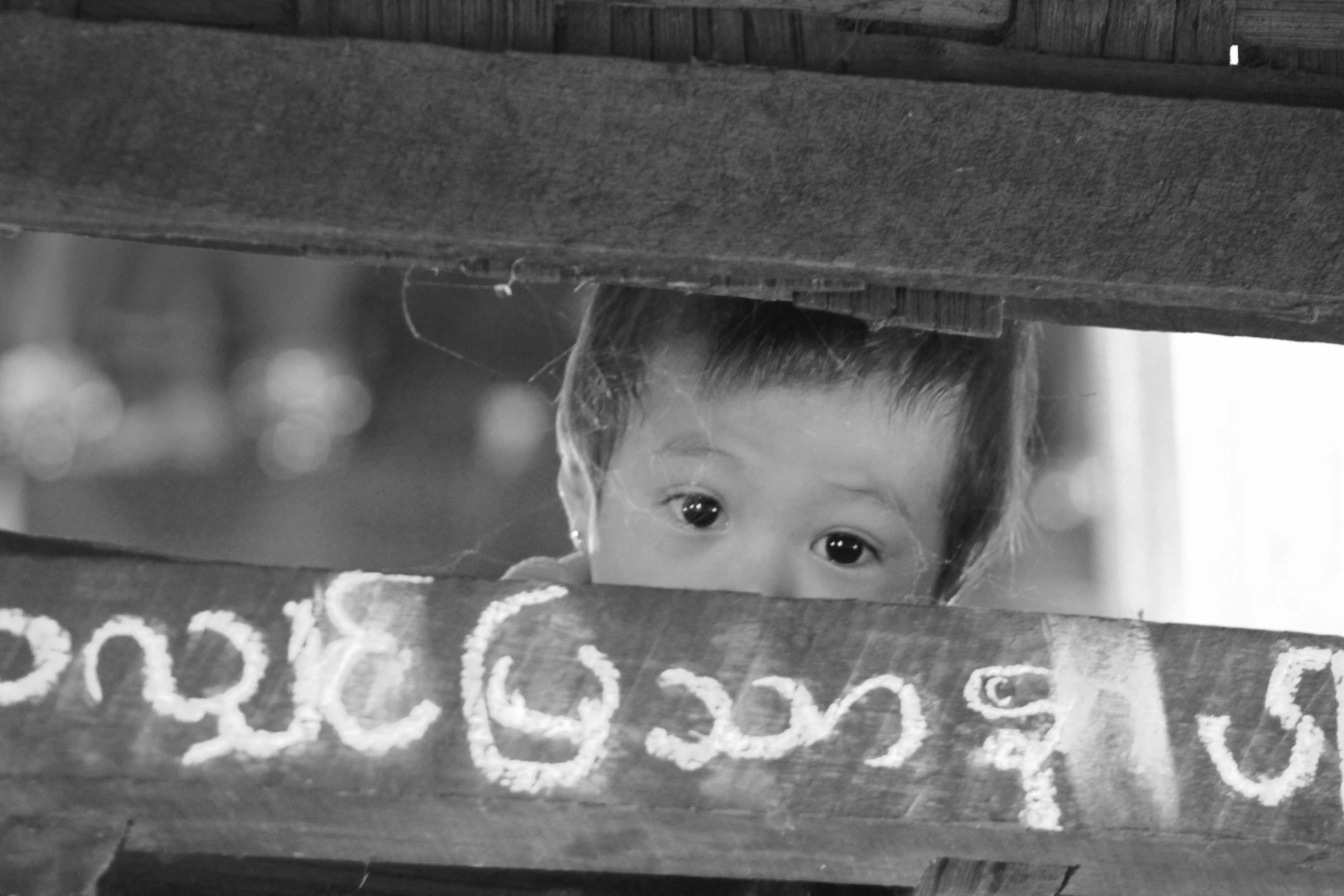 a child stares through a fence at someone