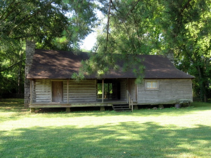 old wooden cabin sitting in the middle of a field