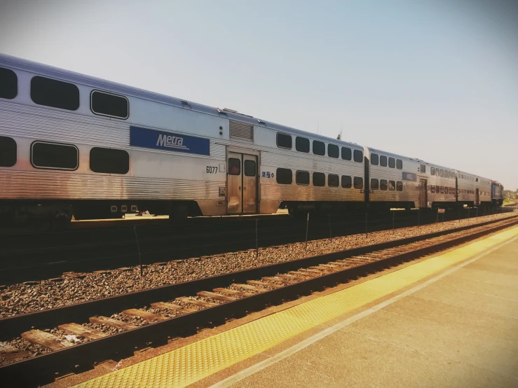 a silver train sitting at a station and a platform