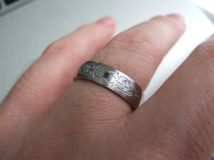 a person's ring on their hand with some sort of design