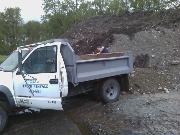 a truck carrying a pile of dirt with a dump on the back