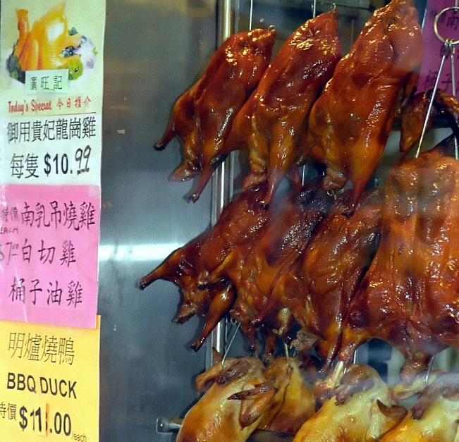 a sign is hanging over some roasted chickens