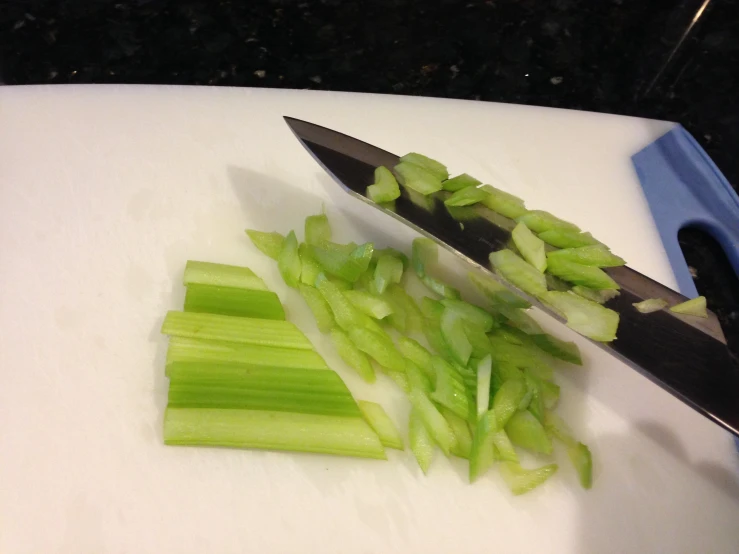 a person chopping green celery on a  board