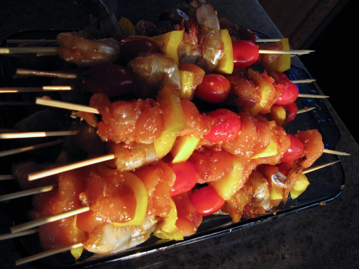 skewered chicken and vegetable food items displayed on black plate