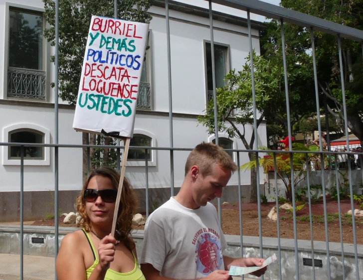 a man holding a sign as a woman stands behind her