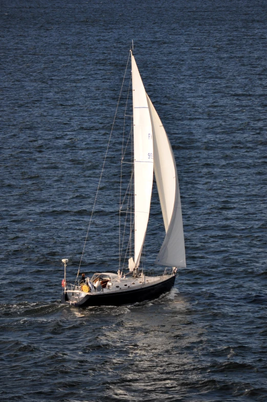 a sail boat with white sails on calm waters