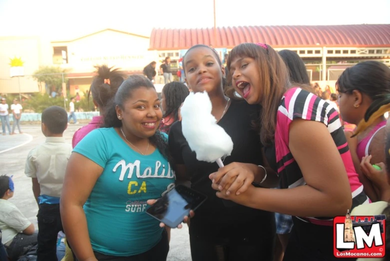 three girls at a street fair, one holding a cotton candy