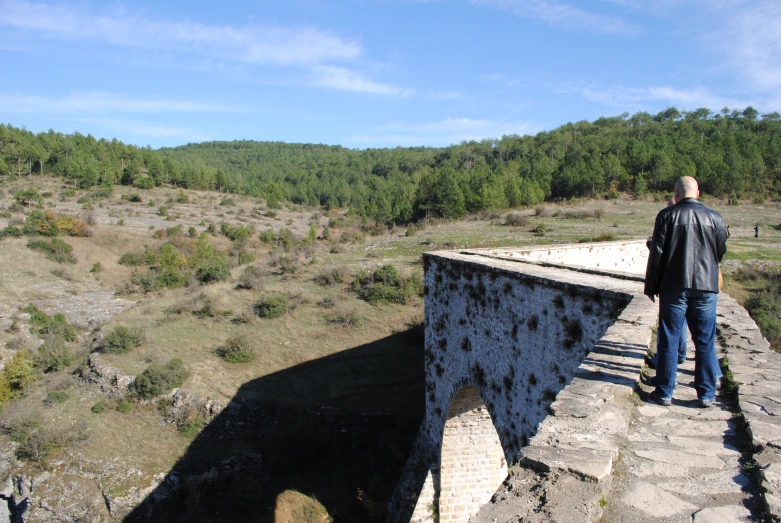 man looking down over top of an old bridge