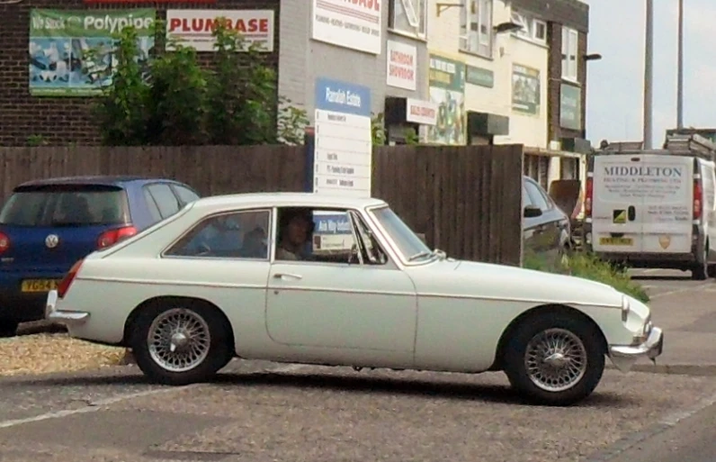 an old fashion white car parked on the side of the road